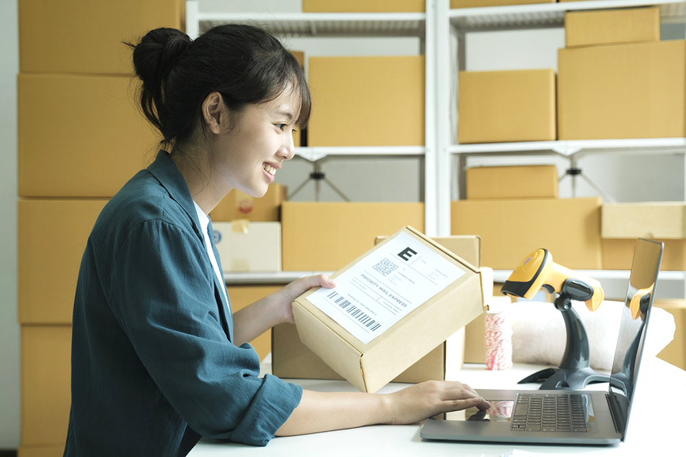 Woman checking parcel address using laptop
